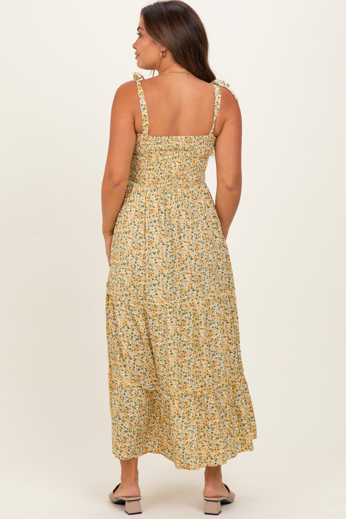 woman wearing a yellow floral maternity maxi dress with adjustable tie straps and a smocked back