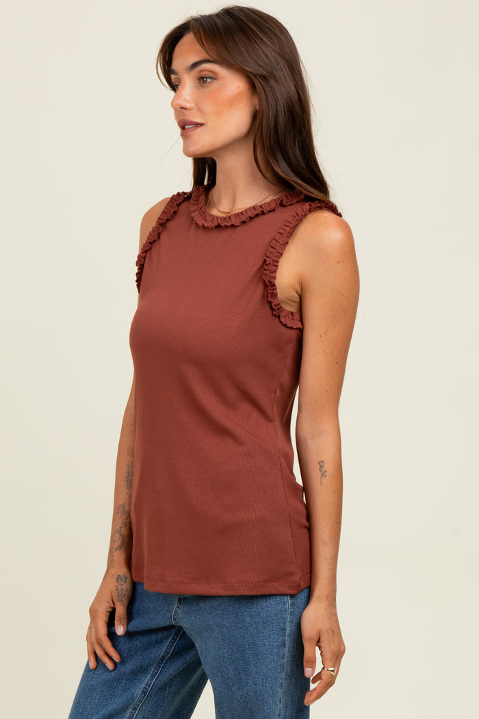 woman wearing a rust-colored tank top with ruffle details on the shoulders, paired with blue jeans
