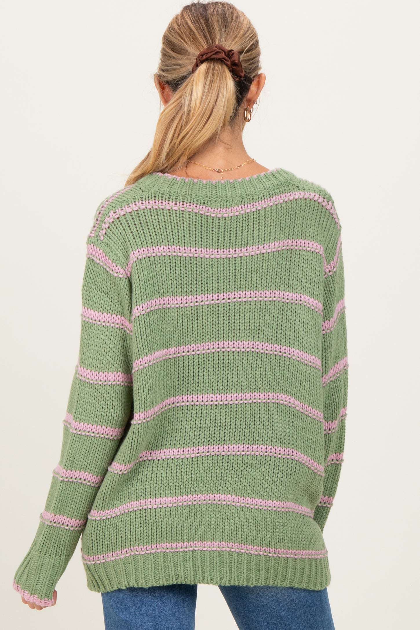 woman wearing a green and pink striped maternity sweater, seen from the back