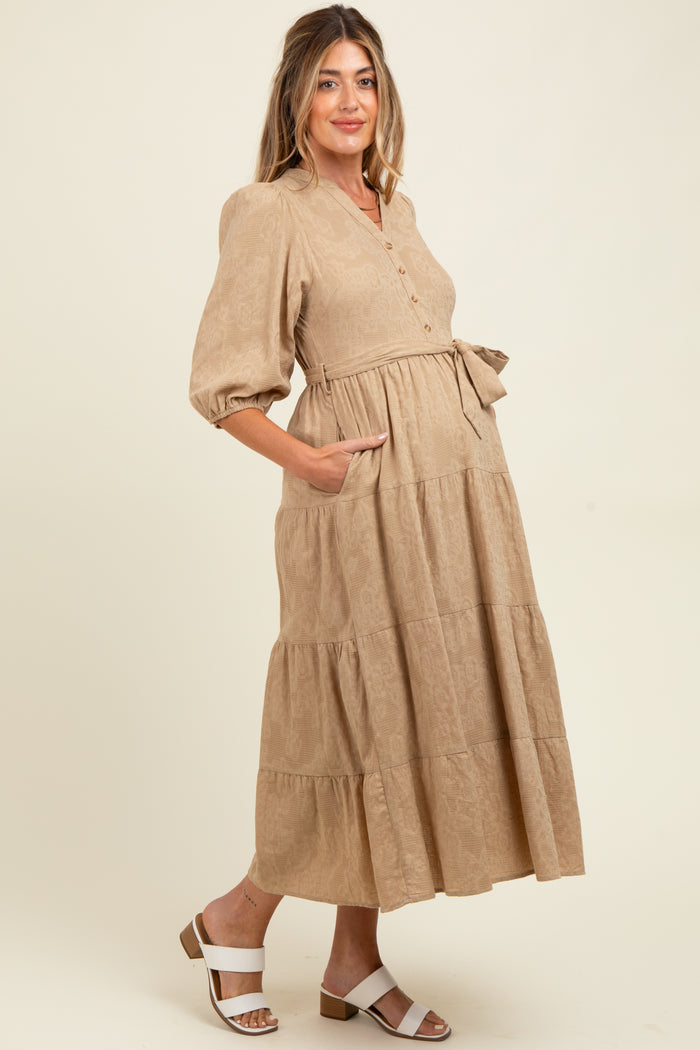 woman wearing a beige tiered maternity dress with buttons and puff sleeves, showing her baby bump