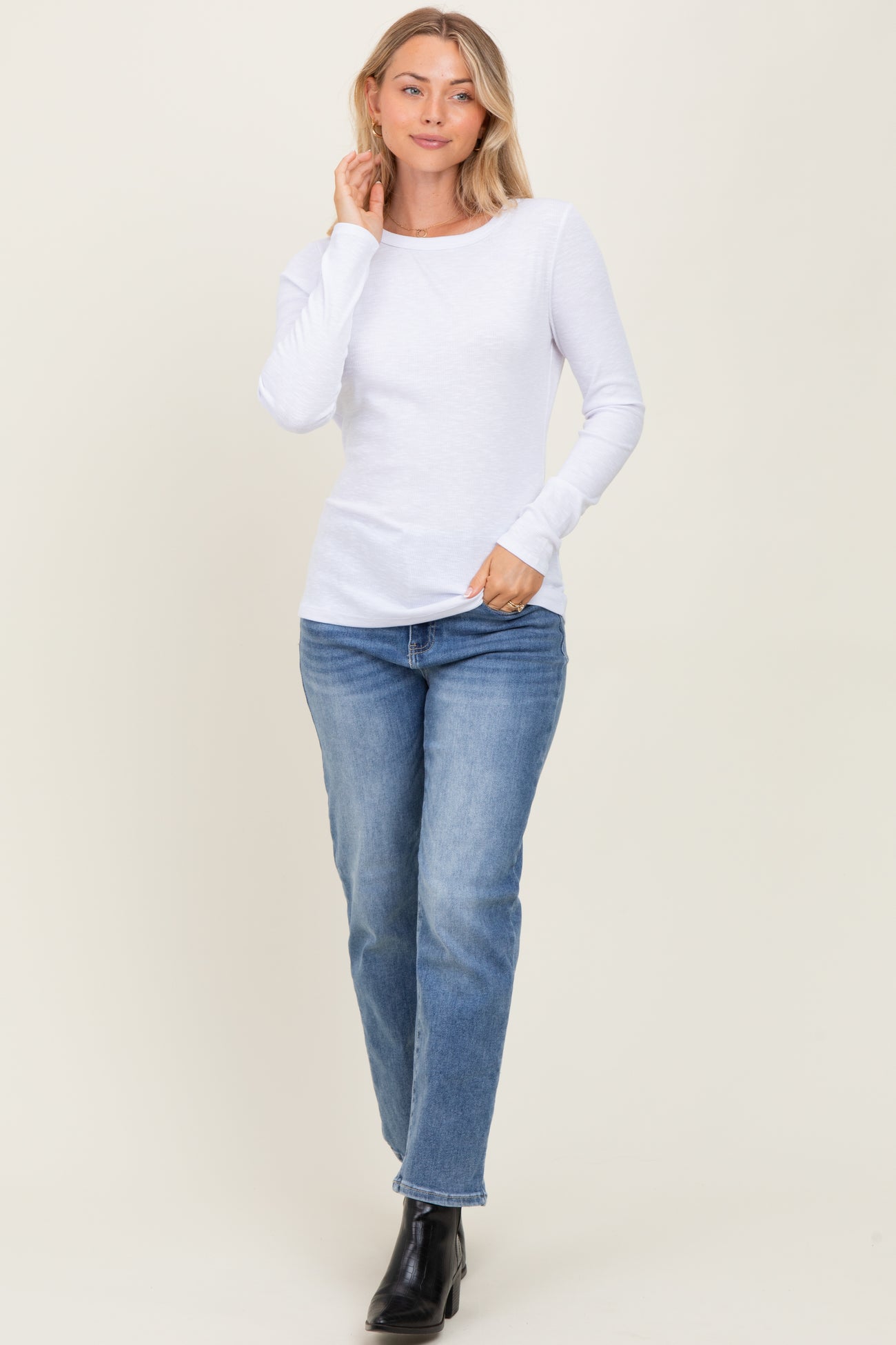 woman wearing a white long sleeve top paired with light wash jeans and black ankle boots
