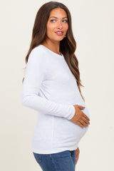 woman wearing a white long sleeve maternity top and holding her baby bump