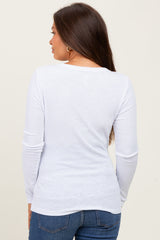 woman wearing a white long sleeve maternity top, seen from the back, paired with blue jeans