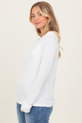 woman wearing a white long sleeve textured top with a relaxed fit, paired with blue jeans