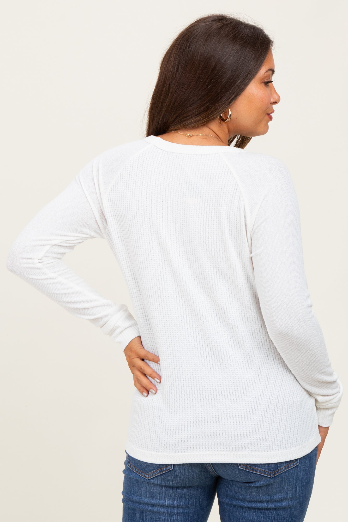 woman wearing a white ribbed maternity top, showing the back view with long sleeves and a relaxed fit