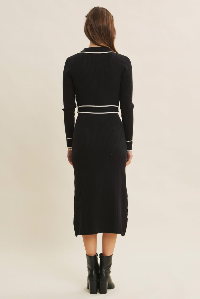 woman wearing a black ribbed midi dress with long sleeves and white accent details, shown from the back