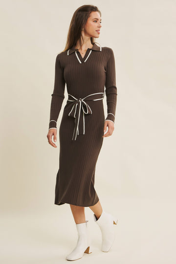 woman wearing a brown ribbed midi dress with a white collar and tie waist, paired with white ankle boots