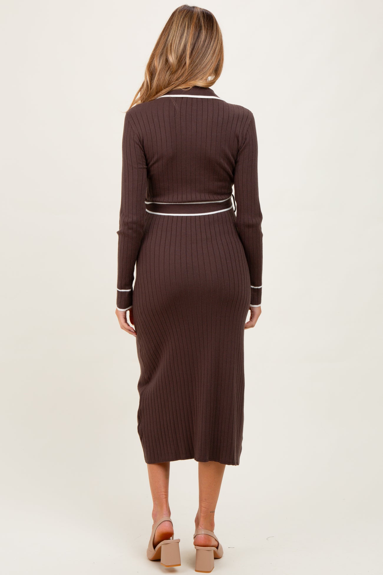woman wearing a brown ribbed maternity dress with a fitted silhouette and long sleeves, showing a pregnant belly