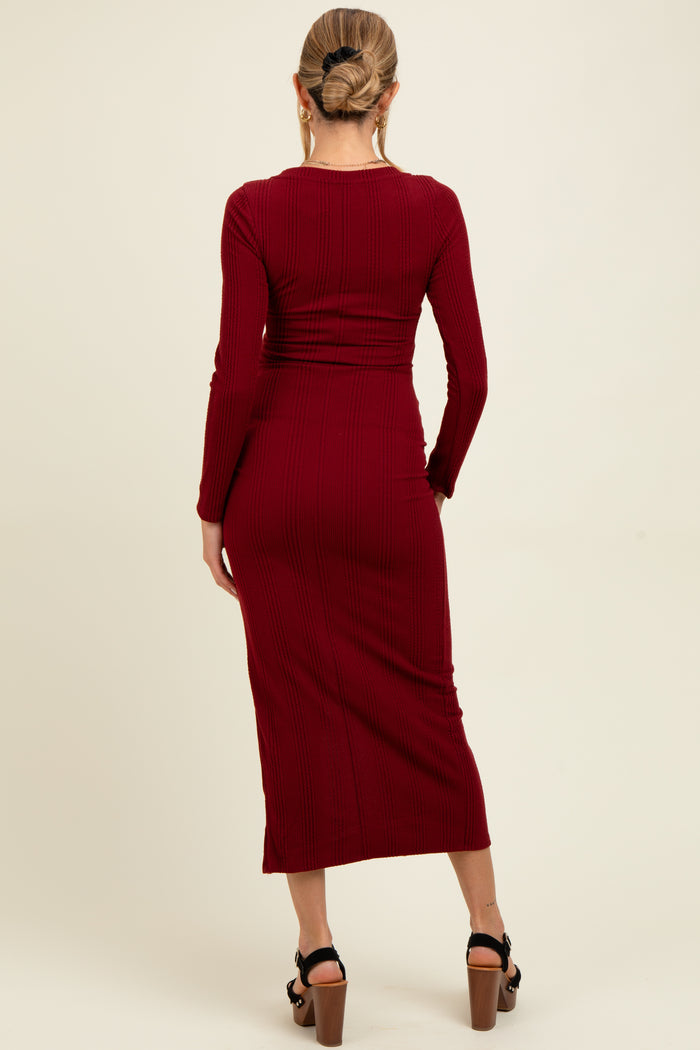woman wearing a ribbed burgundy maternity dress with long sleeves and a fitted silhouette