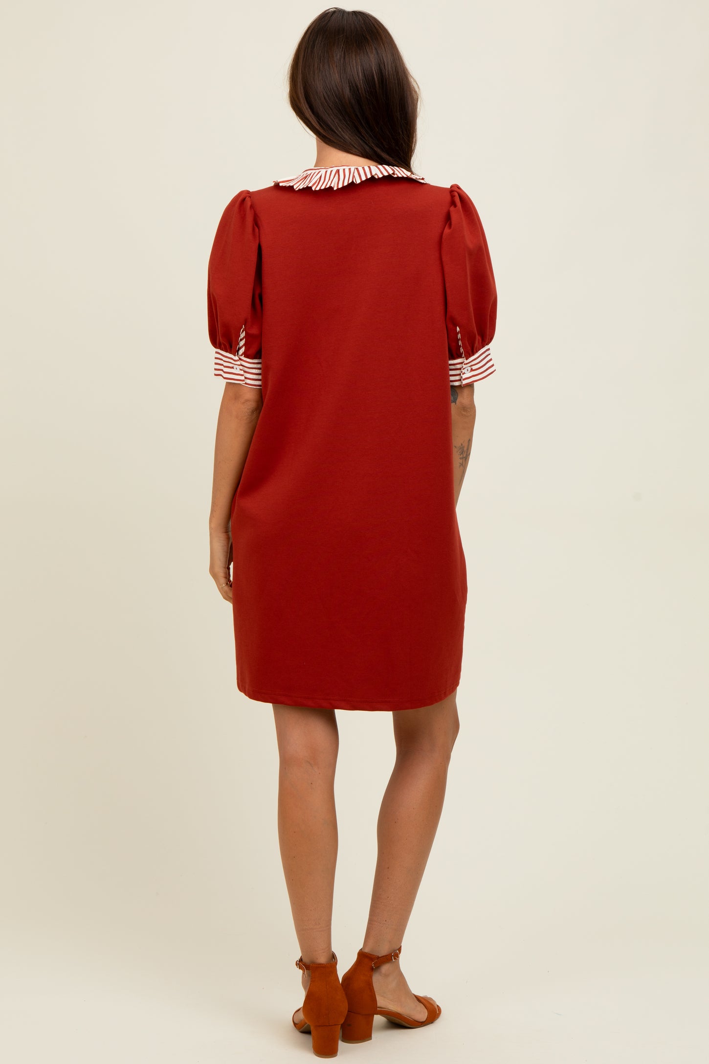 woman wearing a red short sleeve dress with a striped collar and puff sleeves, styled with brown sandals