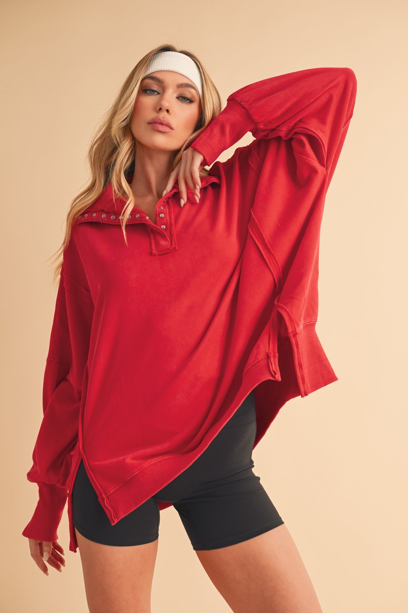 woman wearing a red oversized long sleeve top with button details and black bike shorts