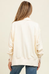 woman wearing a light beige oversized maternity sweatshirt, viewed from the back with relaxed fit and dropped shoulders