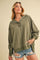 woman wearing an olive green oversized hoodie with a buttoned collar and distressed denim shorts