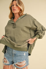 woman wearing an olive green oversized hoodie with button details and distressed denim shorts