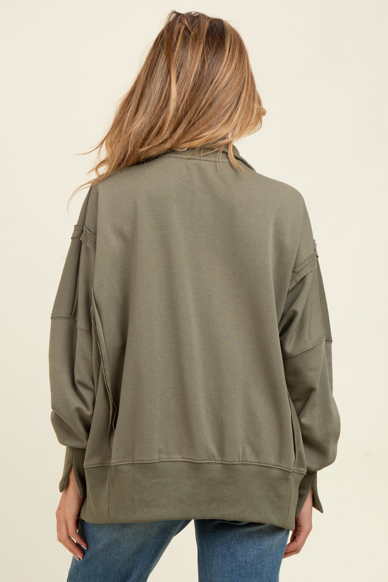 woman wearing a light olive green oversized maternity sweatshirt, seen from the back