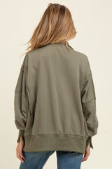 woman wearing a light olive green oversized maternity sweatshirt, seen from the back