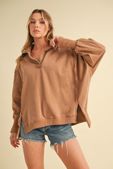 woman wearing a brown oversized pullover sweatshirt with a collar and button details, styled with denim shorts
