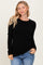 woman wearing a black ribbed long sleeve sweater with a crew neckline and relaxed fit, posing casually
