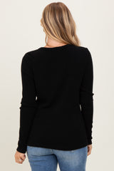 woman wearing a black ribbed long sleeve top, viewed from the back with light blue jeans
