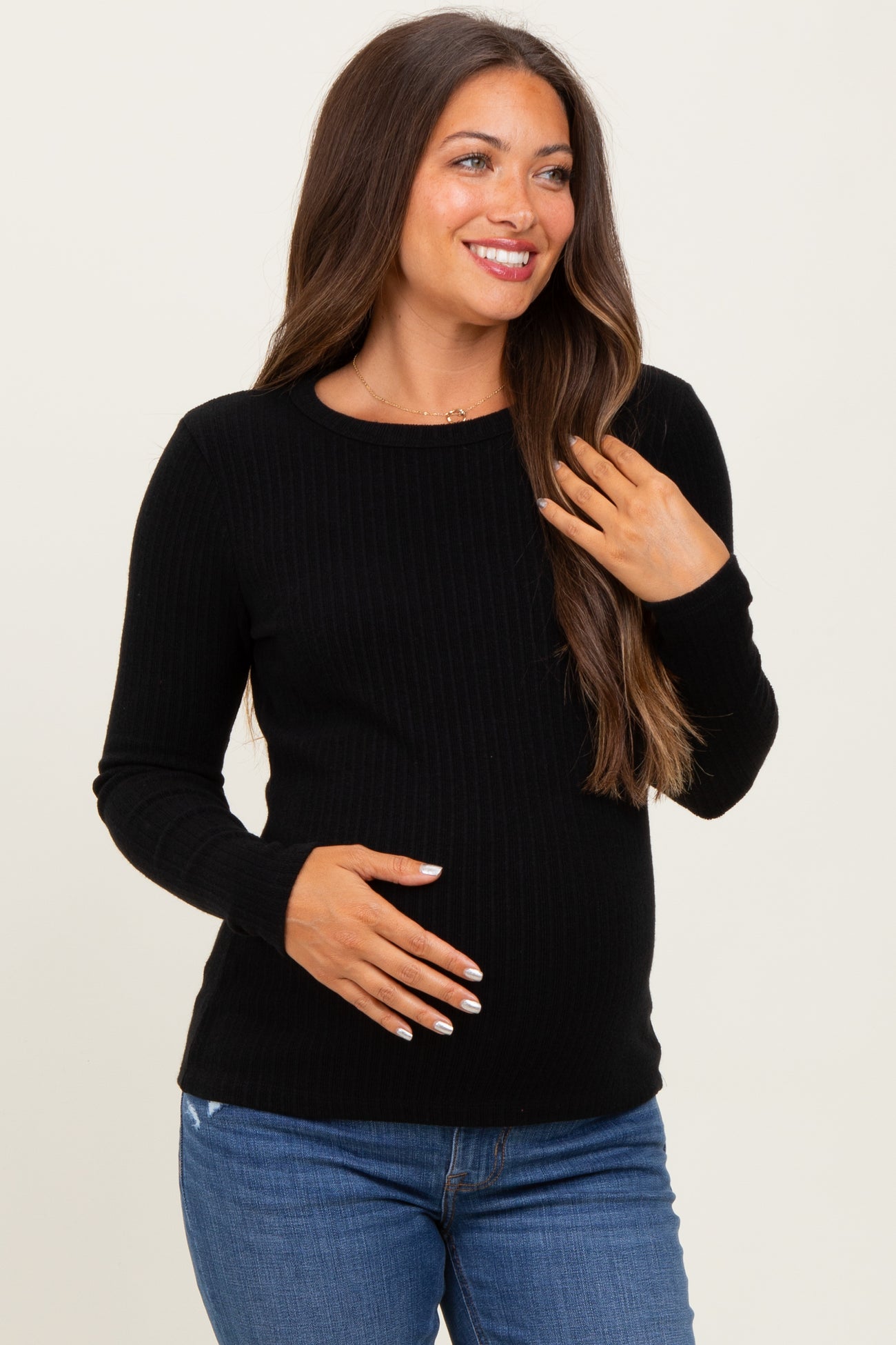 woman wearing a black ribbed maternity top and holding her baby bump