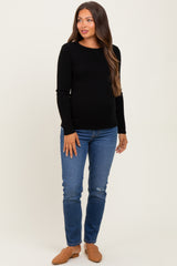 woman wearing a black ribbed long sleeve maternity top and blue distressed skinny jeans with a baby bump visible