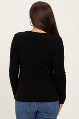 woman wearing a black maternity ribbed long sleeve top, viewed from the back, paired with blue jeans