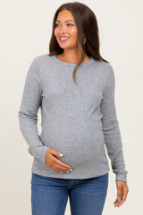 woman wearing a gray ribbed maternity top and holding her baby bump