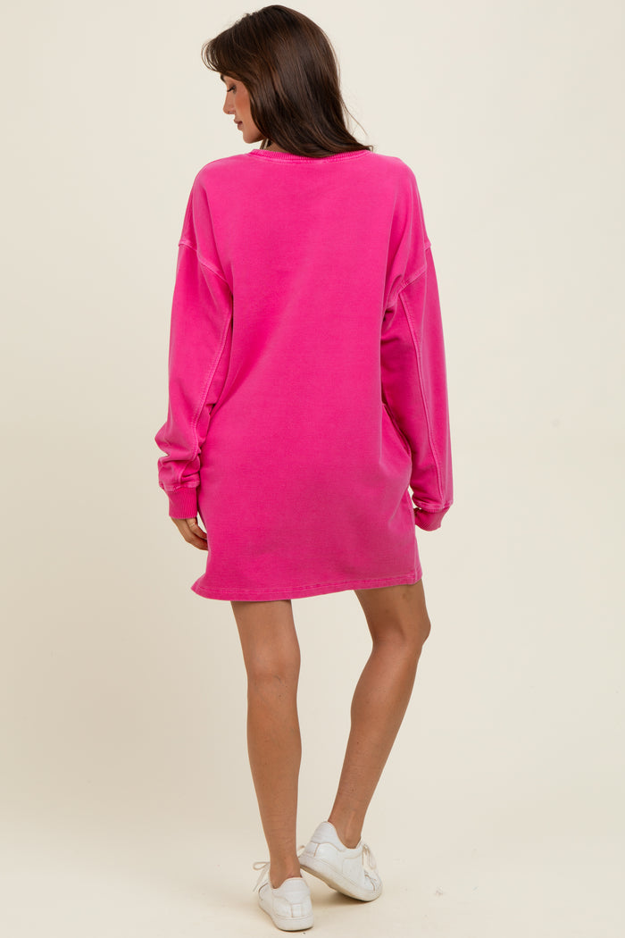 woman wearing a bright pink oversized sweatshirt dress, viewed from the back, with long sleeves and a relaxed fit