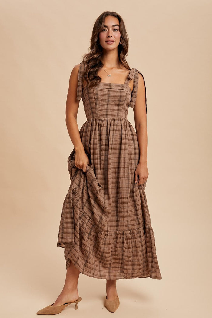 woman wearing a brown plaid midi dress with tie straps and a tiered skirt