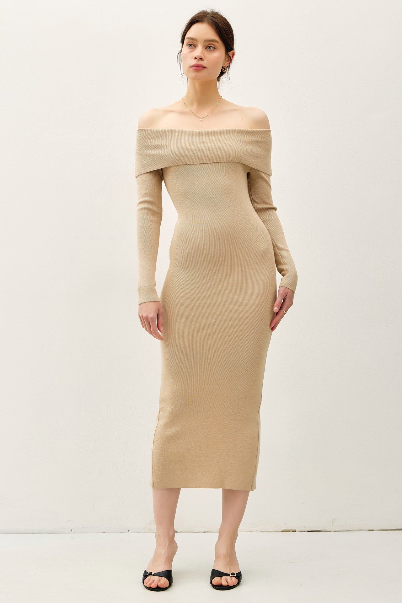 woman wearing a beige off-shoulder fitted midi dress with long sleeves and heeled mules