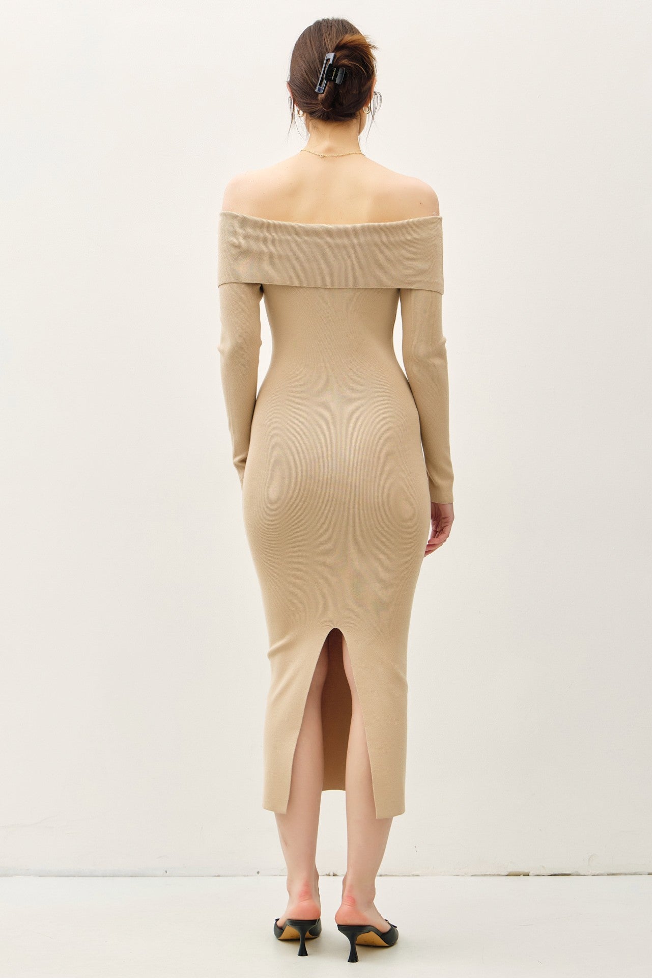woman wearing a ribbed off-the-shoulder beige dress with long sleeves and back slit detail