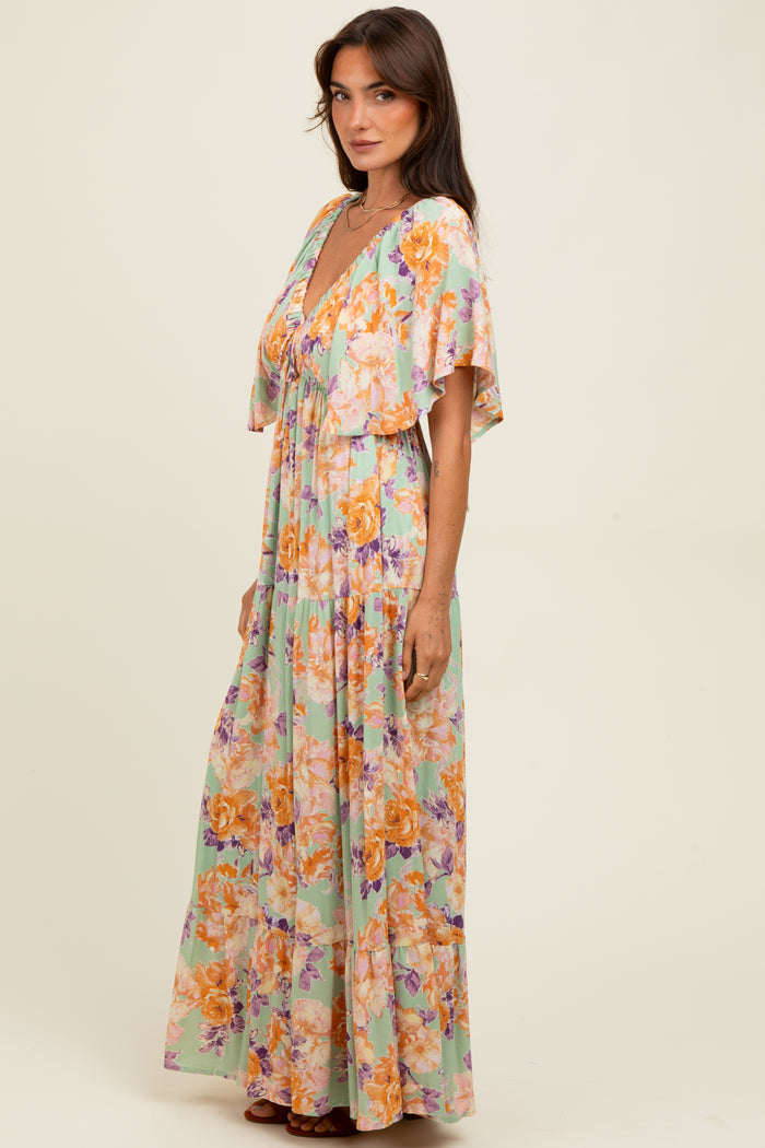 woman wearing a colorful floral maxi dress with a deep v-neck and flutter sleeves