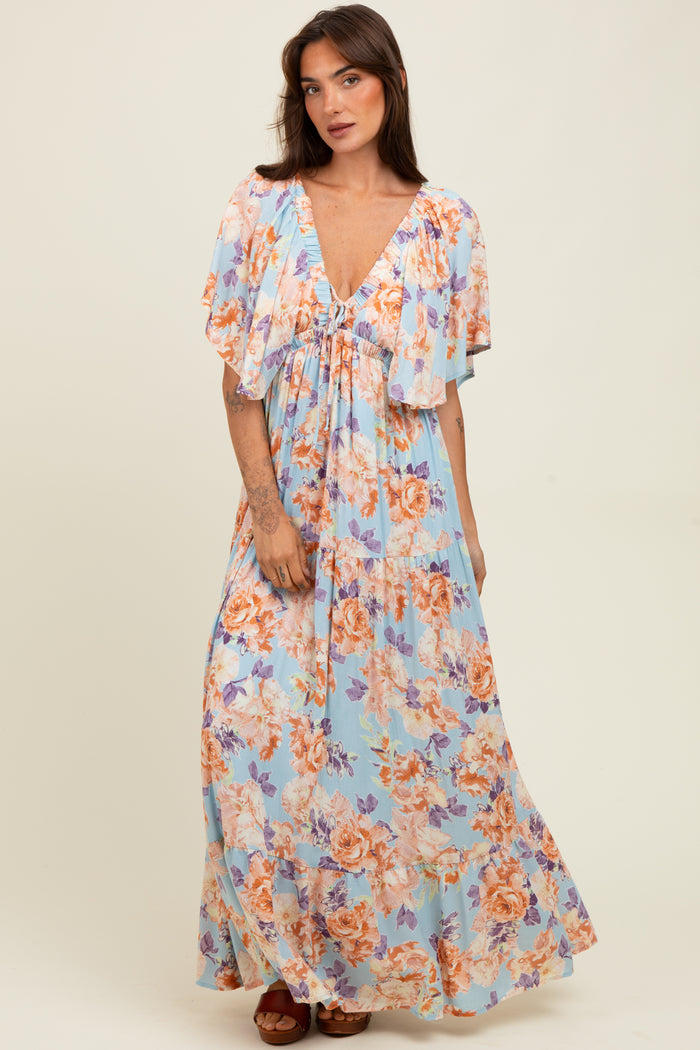 woman wearing a light blue floral maxi dress with flutter sleeves and a cinched waist