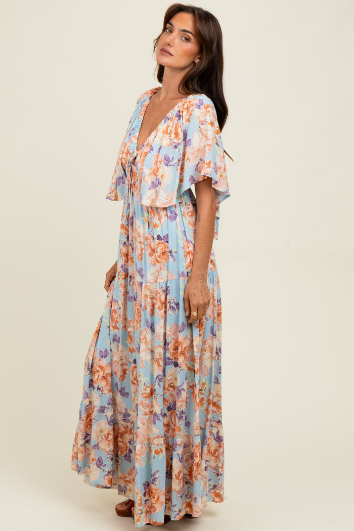 woman wearing a light blue floral maxi dress with flutter sleeves and a deep v-neckline