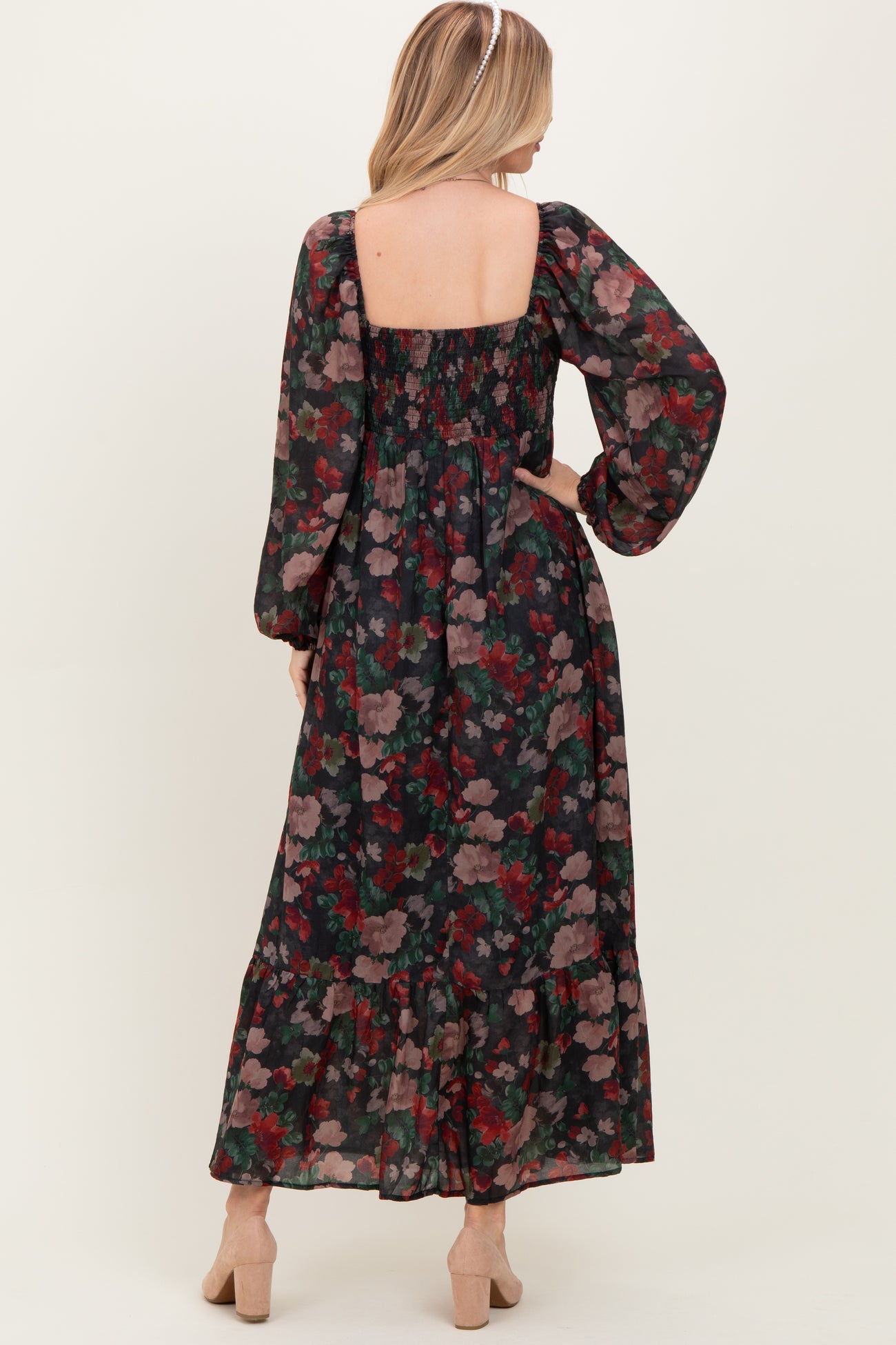 woman wearing a floral maxi dress with long sleeves and a tiered skirt, showing the back view