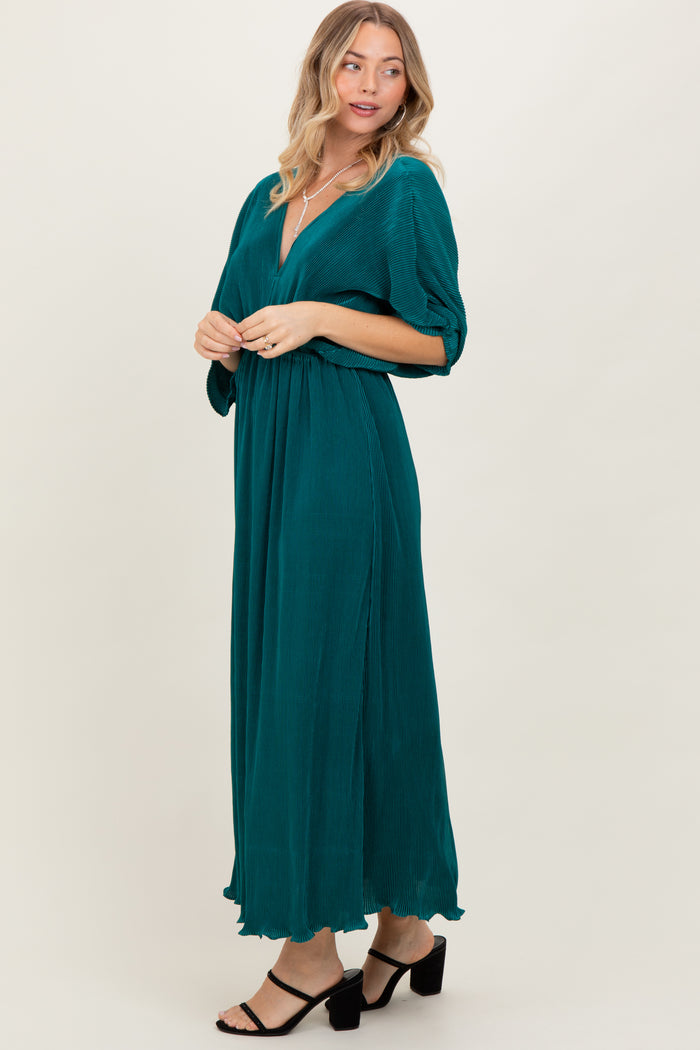 woman wearing a teal maxi dress with a deep v-neck and three-quarter sleeves, styled with black strappy heels