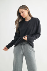 woman wearing a black long sleeve shirt and gray sweatpants with a relaxed fit