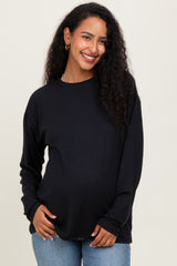 woman wearing a black long sleeve maternity top and showcasing her baby bump