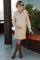 woman wearing a beige maternity sweater dress with a collar and holding her baby bump while posing outdoors