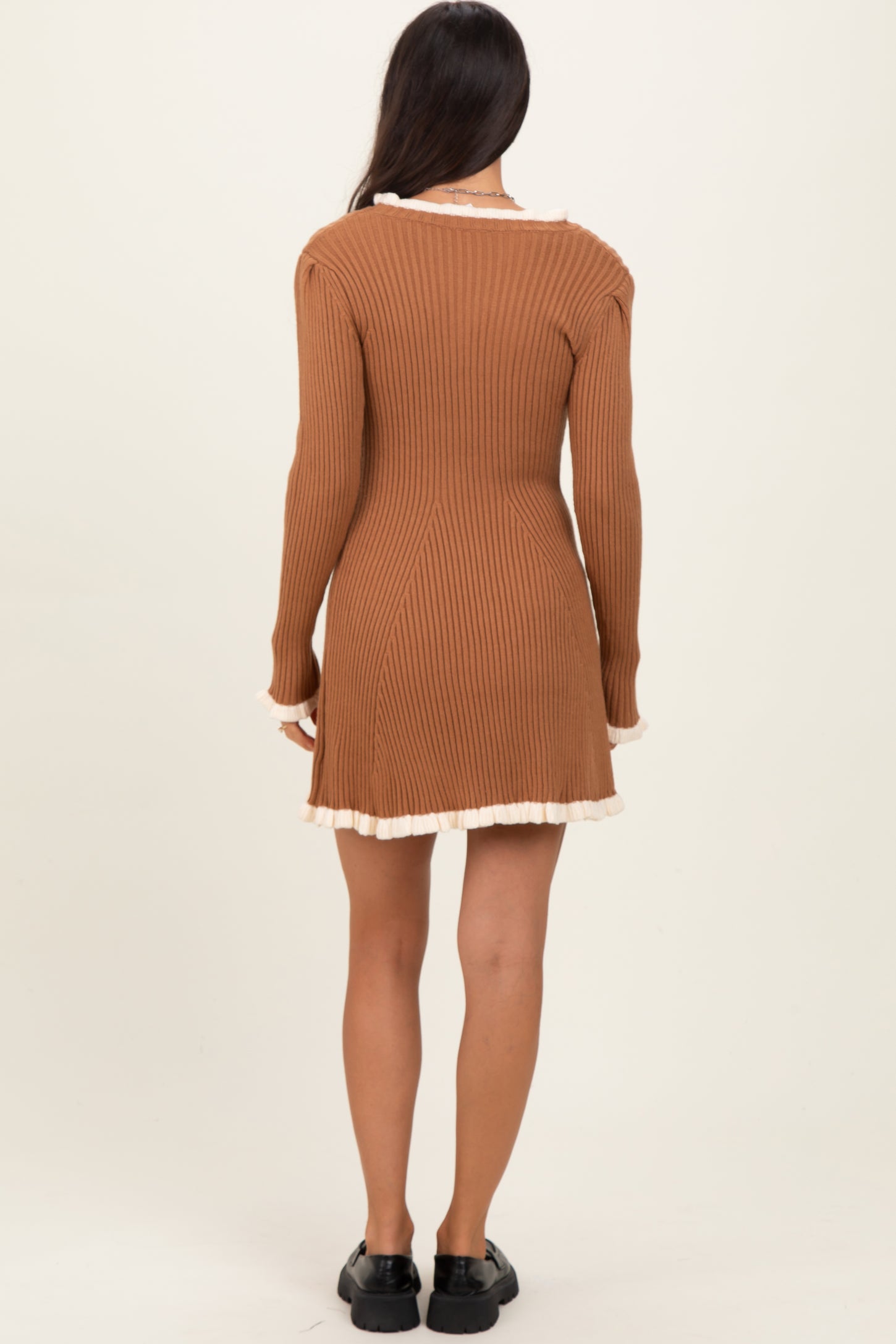 woman wearing a brown ribbed long sleeve dress with a ruffled hem and back detail