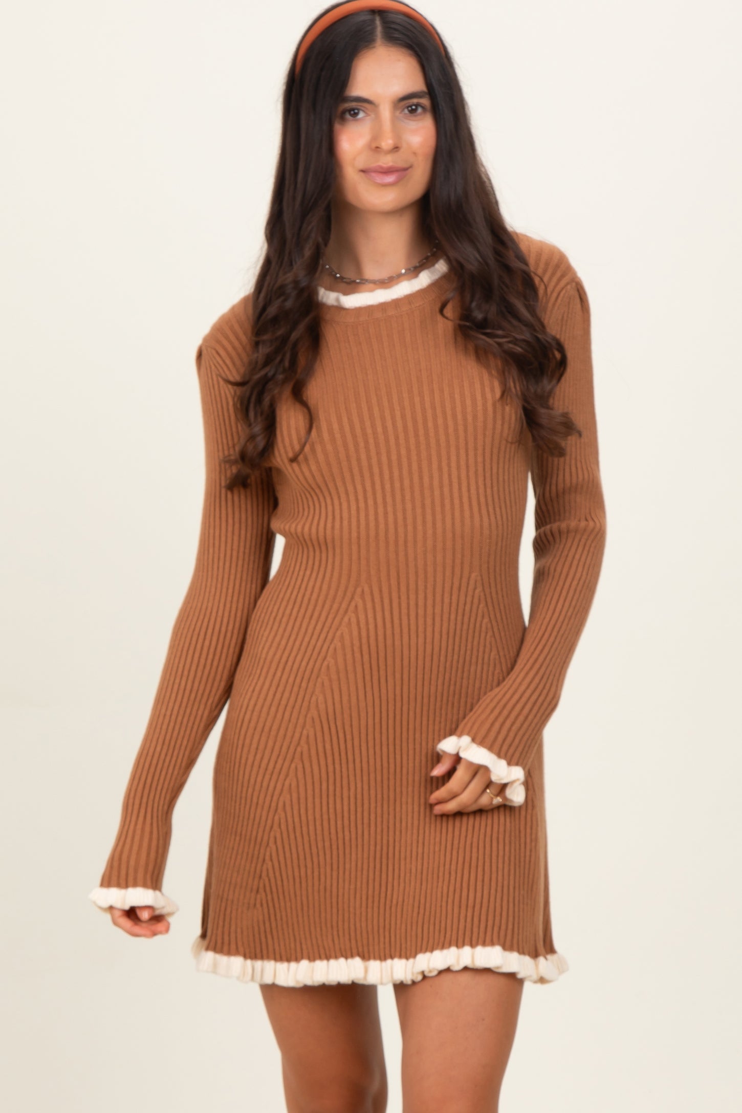 woman wearing a brown ribbed sweater dress with cream ruffle trim details on the neckline and sleeves