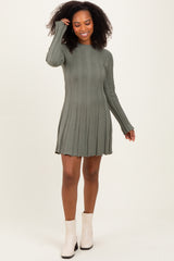 woman wearing a green ribbed long sleeve mini dress with a flared hem and smiling while posing