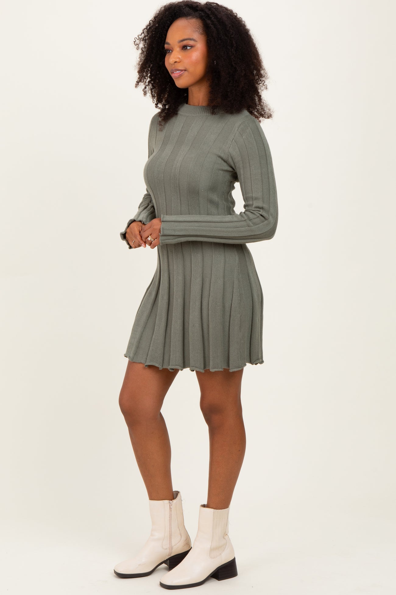 woman wearing a green ribbed long sleeve dress paired with white ankle boots