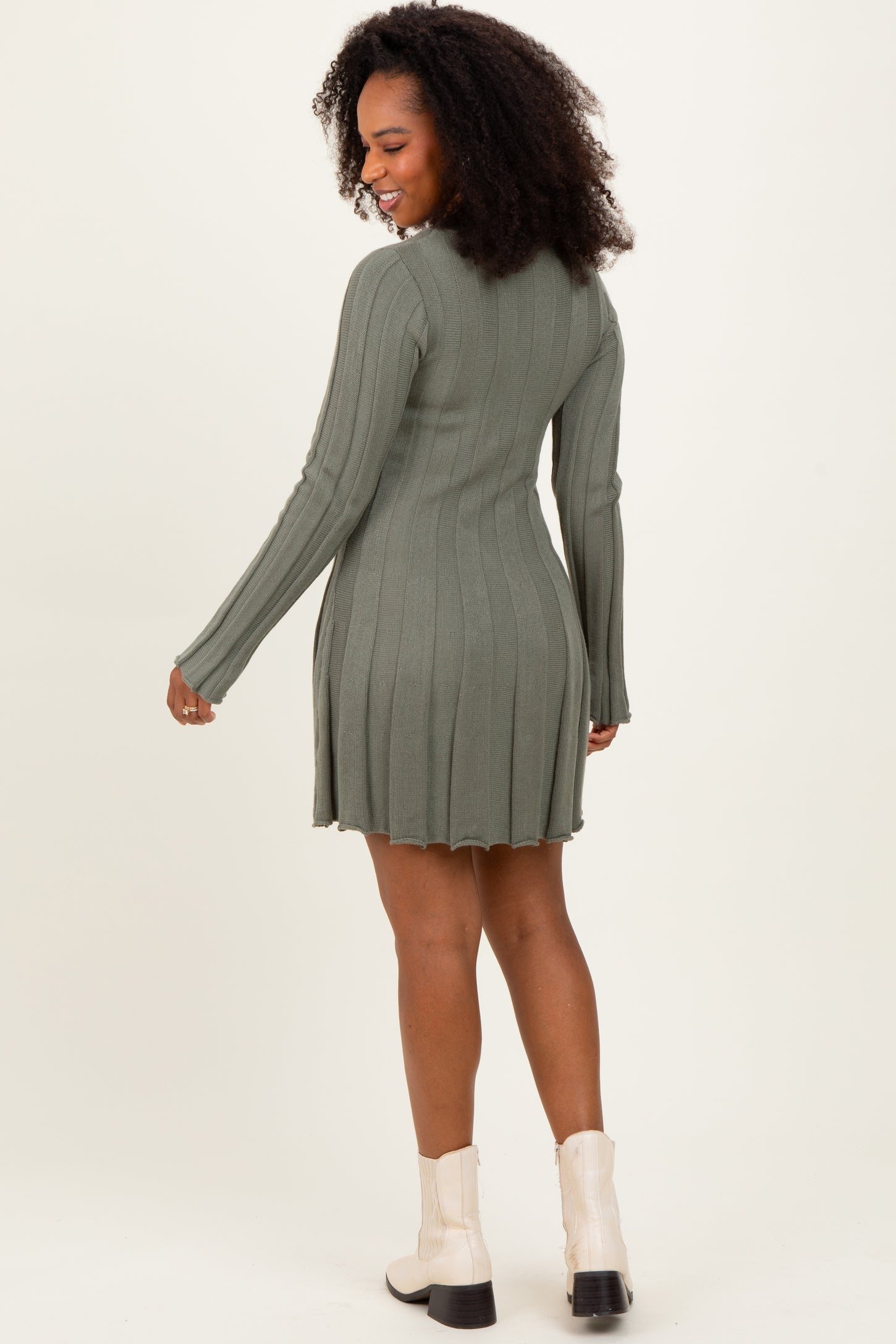 woman wearing a green ribbed long sleeve dress with a flared hem and styled with white ankle boots