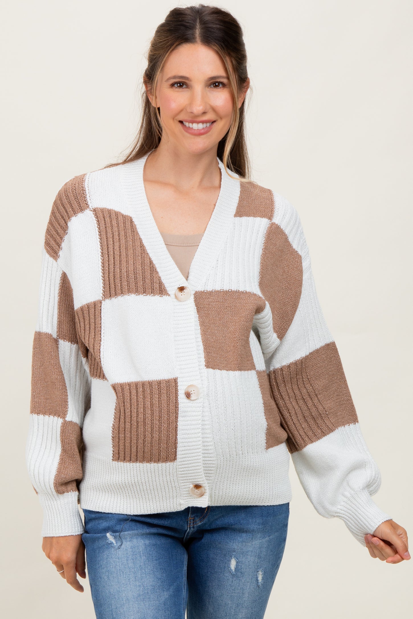 woman wearing a beige and white color block maternity cardigan and showing her baby bump