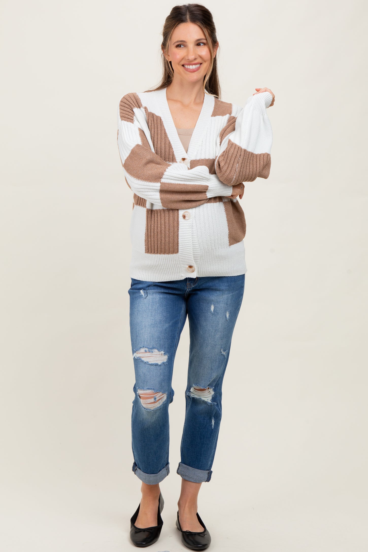 woman wearing a striped brown and white maternity sweater with buttons, paired with distressed blue jeans
