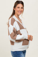 woman wearing a cream and brown checkered maternity cardigan and holding her baby bump