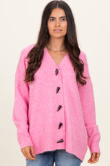 woman wearing a bright pink oversized cardigan with large black buttons and a v-neckline