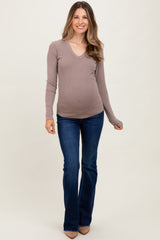 woman wearing a taupe long sleeve v-neck maternity top and flared jeans with a visible baby bump