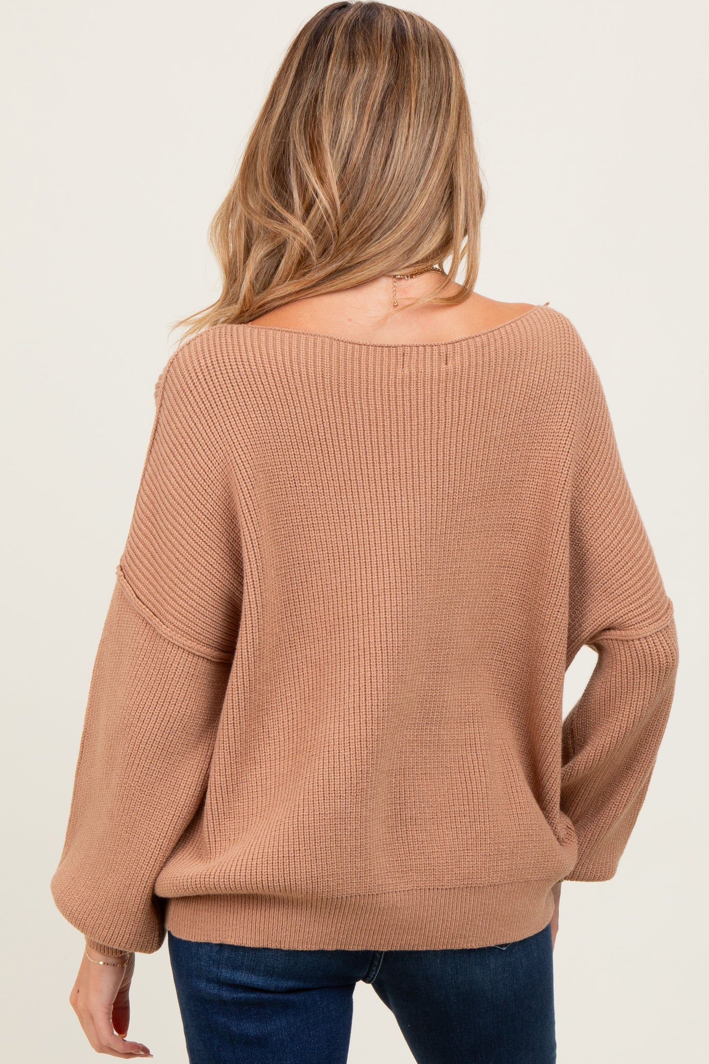 woman wearing a cozy beige maternity sweater with a relaxed fit and loose sleeves, viewed from the back